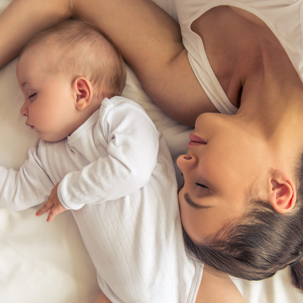Moeder en baby liggen samen in zachte witte babykleding
