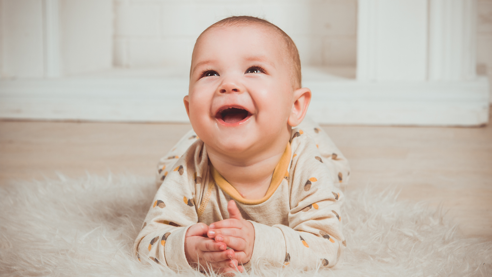 Lachende baby in zachte babykleding op wit kleed